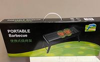 Box of the portable barbecue grill showing product image and branding in black and green design.