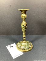 Full view of antique brass candle holder showing its detailed shape and painted decoration.