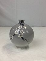 Front view of spherical bud vase decorated with cherry blossom branch design.
