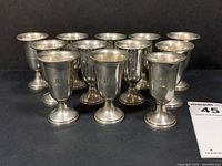 Group of twelve footed cordial cups arranged in rows on black background