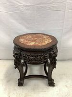 Front view of the carved wooden plant stand showing detailed carving, marble inset top, and claw feet.