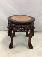 Front angled view showing round marble inset top with carved wooden border, claw feet, and floral carvings on apron and legs.