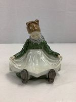 Front view of the Royal Copenhagen Fanoe Girl figurine showing the girl holding her apron open to receive pins or small trinkets.