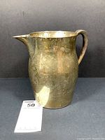 Front-right three-quarter view showing curved body, spout and handle with tarnish