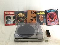 Turntable and vinyl records arranged with dust cover closed, shows all included albums and book