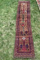 Full view of the Turkish wool runner laid out on grass showing overall pattern and colors, including fringe ends.