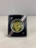 Front view of vintage Ingraham pocket watch mounted on stand, showing black and yellow clock face with silver numerals and decorative diagonal stripes.