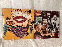 Photo of two vinyl record covers: an orange abstract design and David Bowie's Diamond Dogs album cover showing Bowie and two surreal characters.