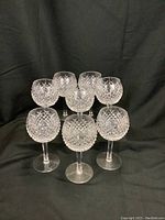 Eight crystal wine glasses arranged in three rows on black backdrop