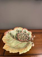 Top-down view of leaf-shaped chip and dip ceramic serving bowl showing the warm green colors and textured leaf detail.