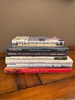 Stack of 7 crafting hardcover books showing titles such as Vogue Dictionary of Crochet Stitches, Marbling, Donghia, French Beaded Flowers, Embroidery, and Textile Style