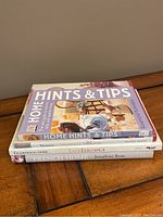 Stack of 4 home decorating books showing spines and colorful covers, on a wooden table.