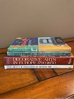 Four painting and decorating books stacked on wooden surface.