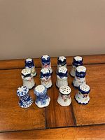 Photo showing full set of 12 ceramic salt and pepper shakers with different blue and white designs on a wooden surface.