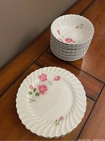 Stack of 6 dinner plates with pink roses and silver trim, flat plate design with scalloped and twisted edges.