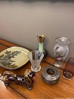 Photo of all items on wooden surface: 5 vases, decorative plate, and ceramic dog figurine