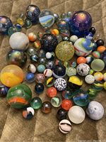 Photo of a large assortment of vintage marbles in different sizes and colors, including glass and stone marbles.