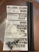 Photo of ReptiBreeze instruction manuals, screws in plastic bag, and black aluminum frame pieces.