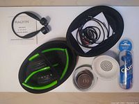 Photo of PowerLocus black/green wireless headphones in a black soft case, Raylin wireless bone conduction headphones with user manual, white and rose gold EWA portable speaker with travel case, wired connection cable, and unopened JVC Gumy wired earbuds package.