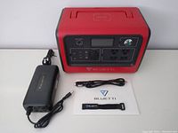 Power station with AC adapter, car cable, strap and manual on white table