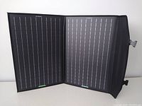 Folded two-panel solar charger laid open showing the black solar cells with grid lines, black fabric border with ECO-WORTHY branding.