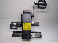 Front view showing dual pedals and central black housing with yellow label