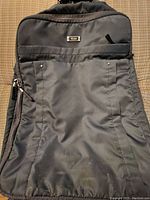 Front view of grey soft shell Tumi carry-on bag showing slightly worn bottom with some discoloration and scratches.