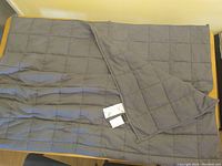 Dark grey weighted blanket spread out showing quilted grid and fabric tags