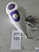 View of handheld massager top showing on/off dial with purple and white body and power cord