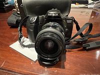 Front view of Minolta Maxxum 400si 35mm film camera with zoom lens attached on a table