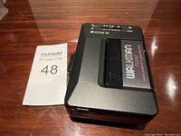 Front view of Sony Walkman cassette player with Sony Walkman cassette inserted on top surface.