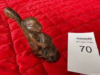 Front angle of one dark brown buffalo horn sculpture showing a stylized Chinese figure, positioned on a red surface next to a lot number card.