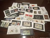 Overview photo of numerous mounted vintage Chinese stamps on white and black cards spread out on a surface.