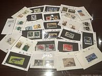Top-down view of multiple vintage Chinese stamps mounted on black and white album cards, showing various designs including portraits and animals.