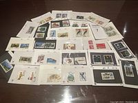 Wide shot showing multiple vintage Chinese postage stamps laid out on a table mounted on white sheets.