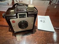 Front and side view of the vintage Kodak Brownie Holiday camera showing lens, body, film advance knob and strap.