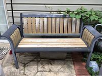 Front view of the outdoor bench showing metal frame and weathered wooden slats with some rust.