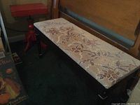 Floral upholstered bench alongside red painted pedestal side table.