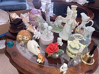 Overhead photo showing a variety of ceramic and glass figurines including cats, rabbits, dancers, swan, and bells on a coffee table.