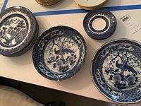 Eight dinner plates and seven saucers in blue and white Blue Willow pattern by Churchill China, displayed on a table.