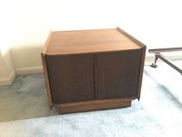 Front and side view showing slatted hinged cabinet doors on two sides beneath a flat wooden top surface of the coffee table.