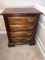 Front view of wooden dresser showing four drawers with brass handles and keyholes, some surface wear visible.