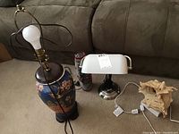 Four table lamps on carpet in front of couch, various styles and sizes.
