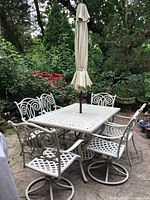 Full view of rectangular table, six chairs and closed umbrella