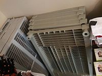 Two off-white plastic shelving units disassembled and stacked resting against a wall