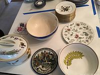 Wide view of plates and bowls including stacked bird plates, lidded Royal Worcester bowl, large mixing bowl, and decorative trivets