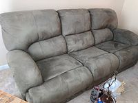 Front angled view of the gray microfiber fabric sofa showing three seats with plush cushion design and reclining end seats.