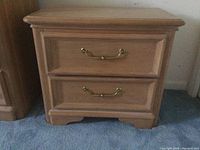Front view of one Stanley wooden nightstand showing two drawers with brass handles and decorative recessed panels.