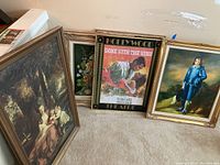 Six pieces of framed wall art leaning against a wall, featuring the Gone With The Wind poster center-front, Blue Boy print on the right, and other assorted classical and floral prints in ornate frames.