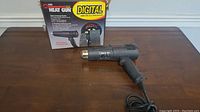 Milwaukee 3300 Digital Heat Gun with original packaging on a wooden surface.